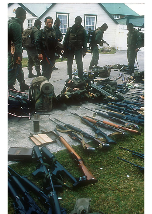Los comandos argentinos recolectan las armas de los soldados británicos y las juntan a un costado de la casa de Hunt, durante la larga mañana del 2 de abril